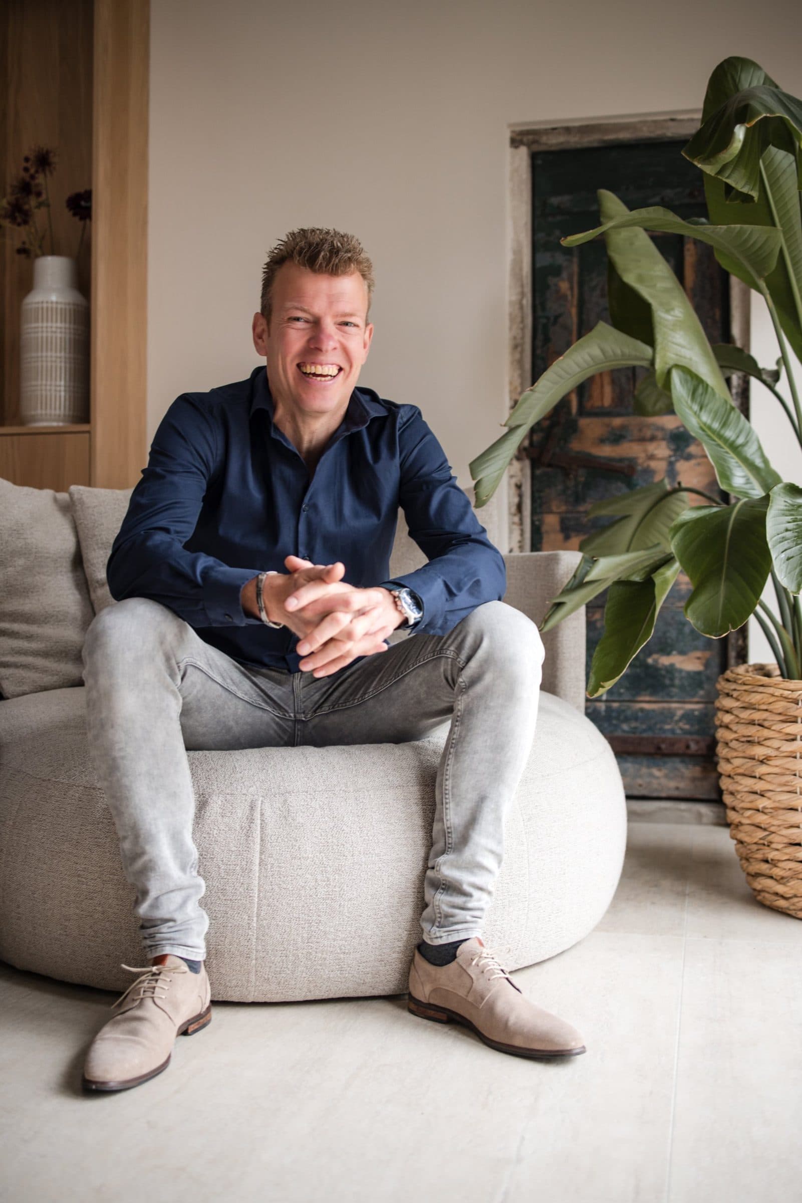 Jaco Golstein lacht, zittend in een lichte woonkamer